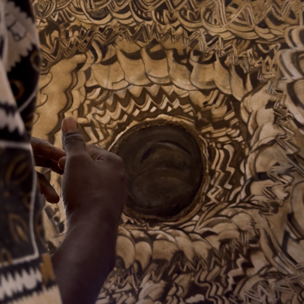 The hands of Vho Avhashoni Mainganye talking through his cow dung painting artwork